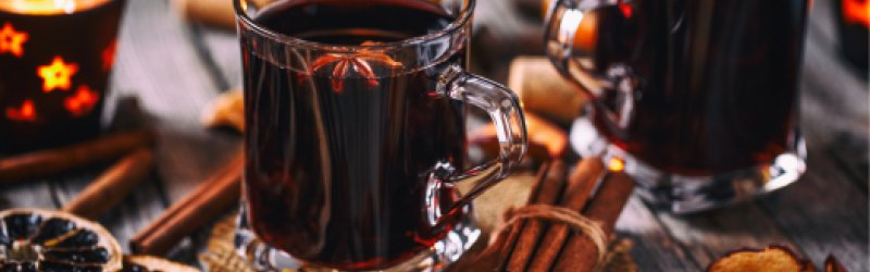 Klassischer Glühwein mit Rotwein auf Hintergrund mit Deko