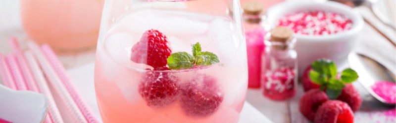 Raspberry Punch im Glas schön angerichtet mit Himbeeren und Minze auf hellem Hintergrund