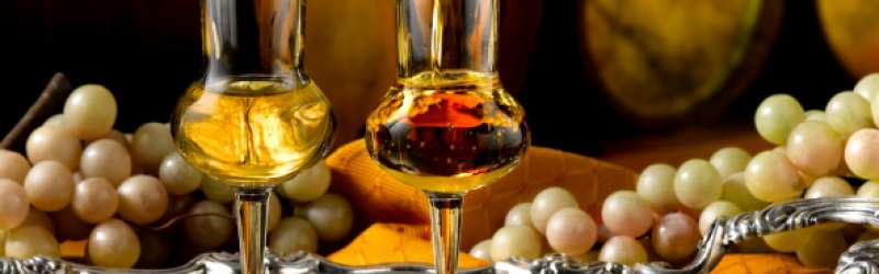Zwei Gläser mit Grappa auf Tablett mit Trauben