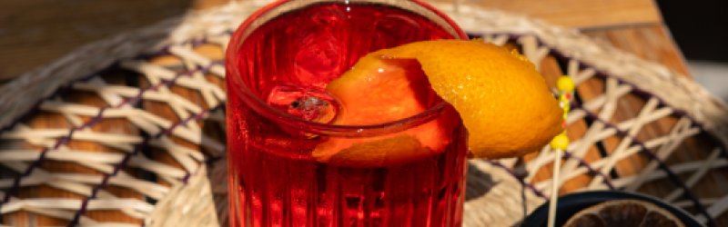 Negroni im Glas mit Orangenschale auf hellem Hintergrund