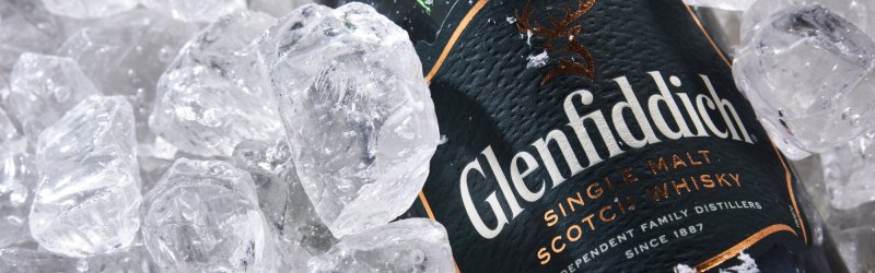 Une bouteille de whisky Glenfiddich repose sur des glaçons, l'extérieur étant recouvert d'un peu de neige.