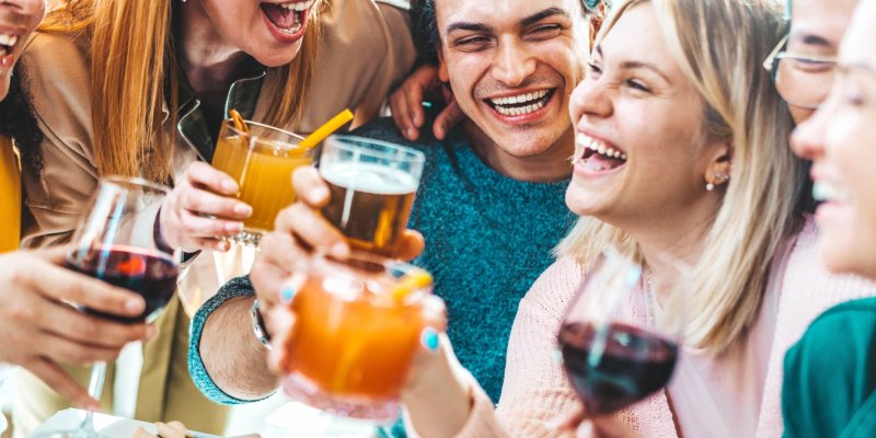 Menschen prosten einander mit verschiedenen Getränken fröhlich zu, während sie lachen und gesellig sind.