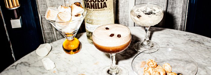 Gläser mit Cocktails stehen auf einem Marmortisch, umgeben von Popcorn und Marshmallows.
