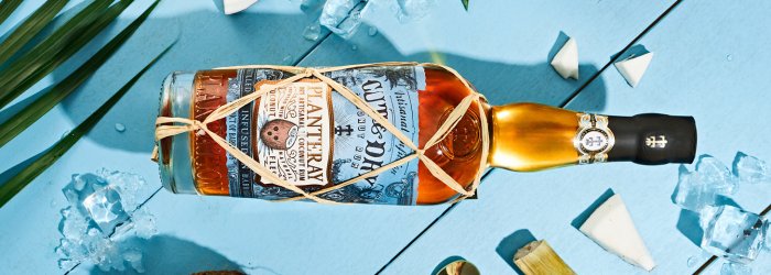 EIne Rum Flasche auf einem Holzfass in einem Lagerraum mit mehreren Fässern im Hintergrund  