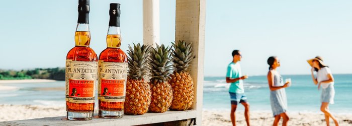 A rum bottle on a table with lots of plants next to it