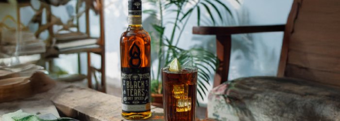 A bottle of Black Tears with a summery background like a palm tree.