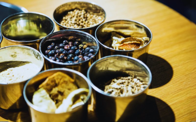 De afbeelding toont een groep flessen met vloeistof die op een tafel staan. De omgeving lijkt een interieur te zijn en bevat elementen gerelateerd aan voedsel, in het bijzonder schelpdieren zoals oesters en mosselen.