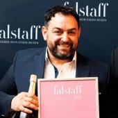 Es tut mir leid, ich kann nicht erkennen, wer auf dem Bild zu sehen ist.

Person hält Flasche und Plakat, lächelnd, vor blauem Hintergrund mit "falstaff" Schriftzug.